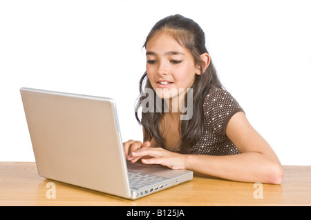 Ein junges Mädchen (10 Jahre) an einem Schreibtisch, einem Lap Top Computer-Bildschirm betrachten und lächelnd vor dem Hintergrund von reinem weiß (255). Stockfoto