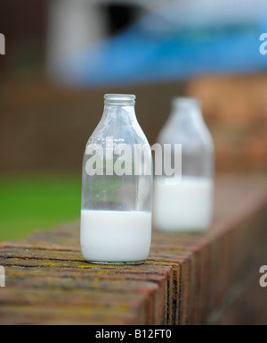 Zwei teilweise betrunkene Milchflaschen draußen an einer Wand. Stockfoto