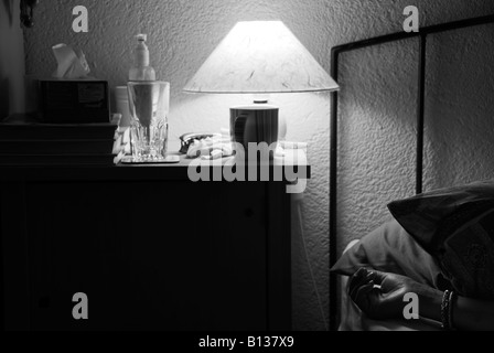 Stock Foto einer Womans Hand wie sie in ihrem Bett schläft gibt es ein Nachttisch mit einer Nachttischlampe und einer Teetasse Stockfoto