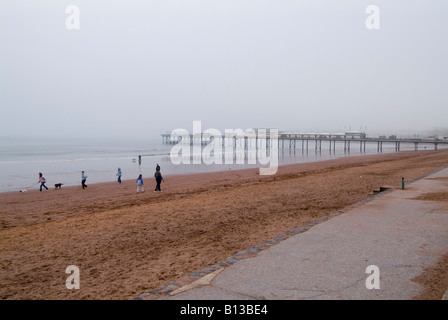 Strand mit Spaziergängern und dem Pier an einem nebligen Wintertag, Paignton, Devon. VEREINIGTES KÖNIGREICH Stockfoto