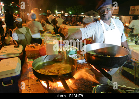 eine lokale Chef kochen bis ein Fisch braten auf dem Fischmarkt Oistins in Bridgetown, Barbados Stockfoto