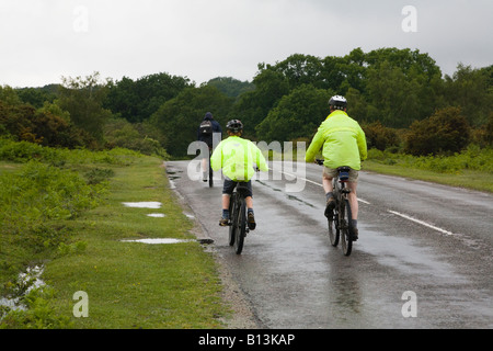 Familie Radfahren auf einer Landstraße. Ferienzeit. Nassen elenden Tag im New Forest, Hampshire, UK. Stockfoto