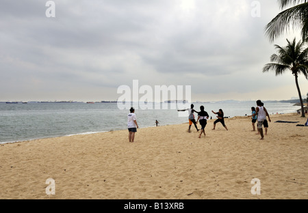 Jugendliche spielen Sepak Takraw auf dem Strandsand im East Coast Park in Singapur Stockfoto