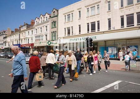 Masse der Leute mit Pelikan Fußgängerüberweg über eine Hauptstraße in der Innenstadt. Mostyn Street North Wales Llandudno GROSSBRITANNIEN GROSSBRITANNIEN Stockfoto