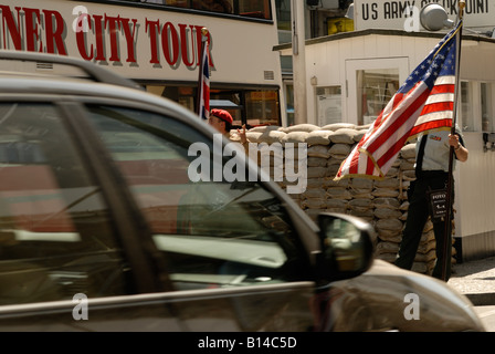 Berlin. Checkpoint Charlie heute. Alliierten Streitkräfte Grenze Kontrollpunkt. Schauspieler als amerikanischer Soldat posiert mit amerikanischen Flagge. Stockfoto