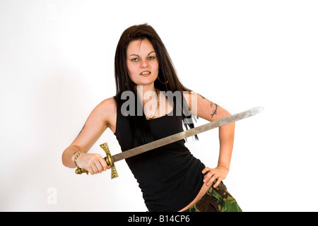 Eine Frau im Kampf gegen Hosen und eine schwarze Weste Top schwingt ein Schwert. Stockfoto