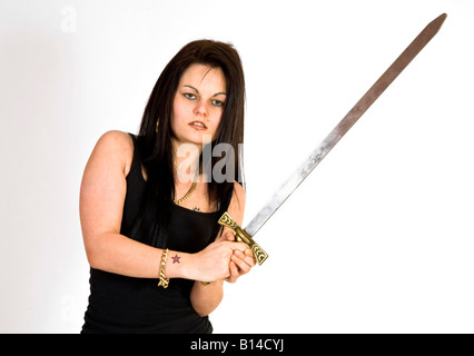 Eine Frau im Kampf gegen Hosen und eine schwarze Weste Top schwingt ein Schwert. Stockfoto