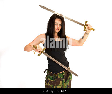 Eine Frau im Kampf gegen Hosen und eine schwarze Weste top schwingt zwei Schwerter. Stockfoto