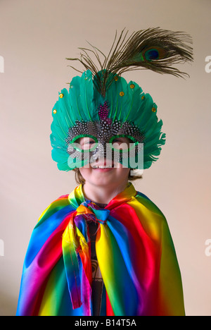 Ein Junge in Kostüm tragen eine weichkantige Maske und einen Regenbogen-Umhang Stockfoto