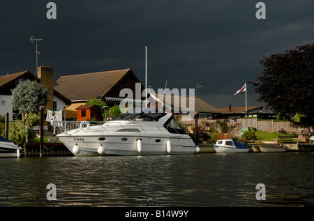 Große weiße Motoryacht vor Anker vor am Flussufer-Häusern unter schwarzen bedrohlichen Himmel, Themse, Walton on Thames, Surrey Stockfoto