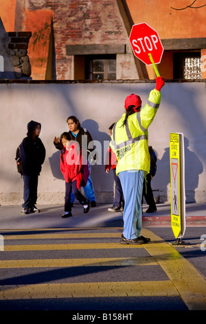 Spanisch Schule Kreuzung Wache steuert Straßenverkehr als Süd-Kalifornien Grundschüler und Eltern kommen in AM Stockfoto