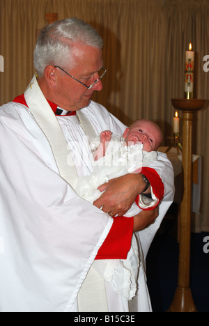 Katholischer Priester mit Baby zur Taufe, Gosport, Hampshire, England, Vereinigtes Königreich Stockfoto