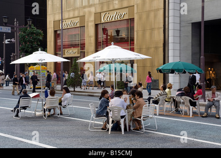 Leute sitzen an Tischen unter den Sonnenschirmen auf der Hauptstraße in Ginza am Wochenende wenn Straße eine in Tokyo 2008 Fußgängerzone ist Stockfoto