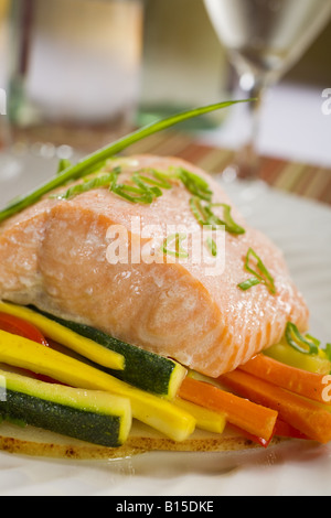 Filet vom Lachs, gebacken, über bunte Gemüse mit Brille unscharf im Hintergrund Stockfoto