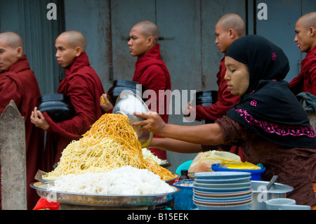 Buddhistische Mönche übergeben eine Garküche auf dem Weg zu ihren morgendlichen gehen Almosen in Zentrum von Yangon/Myanmar, Burma Stockfoto