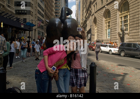 Touristen posieren für Fotos vor der Wall Street Bull am Broadway in Lower Manhattan in New York Stockfoto