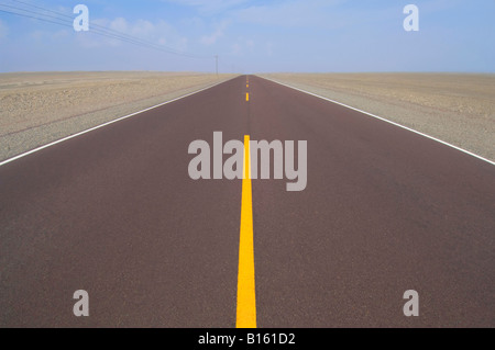 Teil der Pan-American Highway in der Wüste zentriert und führen aus der Distanz mit gelben Trennlinien und blauer Himmel. Stockfoto