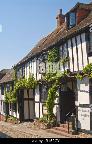 Vertikale Weitwinkelaufnahme der traditionellen Tudor Cottages auf einer gepflasterten Straße in Roggen an einem sonnigen Tag. Stockfoto