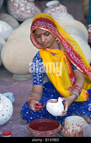 Rajasthani Frau malt einen Ton-Topf für das GANGUR FESTIVAL in JOHDPUR RAJASTHAN Indien Stockfoto