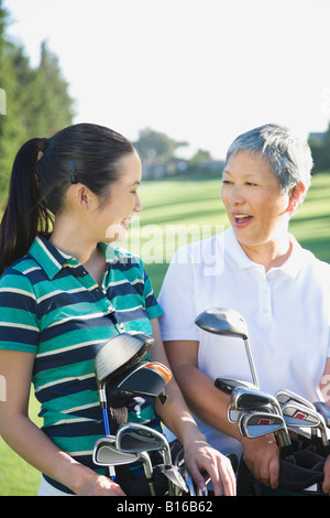 Asiatische Mutter und Erwachsene Tochter hält Golftaschen Stockfoto
