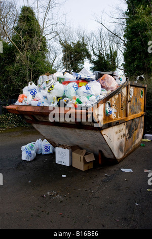 Überladenes Recycling skip, voll nach oben (Müll und Müll weggeworfen, Plastiktüten, Kartons, die Boden verschmutzen) - Baildon, Yorkshire, England. Stockfoto