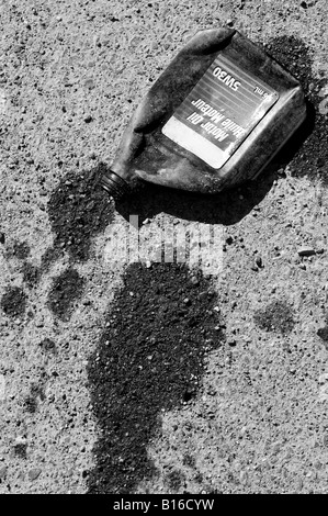 Eine Flasche gequetscht Motoröl schwappt seinen Inhalt auf dem Bürgersteig Stockfoto