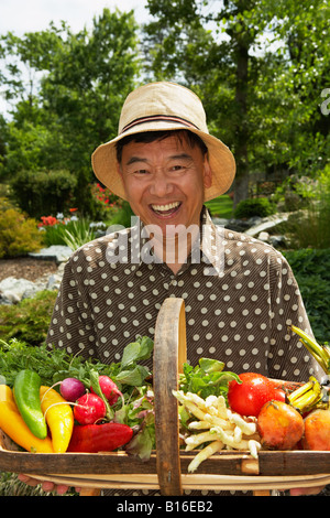 Senior asiatischen Mann, hält Korb mit Gemüse Stockfoto