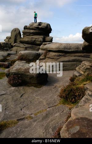 Eine Person stand auf über Owler Tor ein Gritstone-Aufschluss im Peak District in Derbyshire Stockfoto