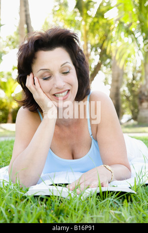 Hispanic Frau liest in Rasen Stockfoto