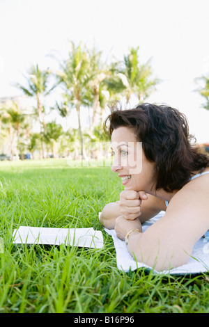Hispanic Frau liest in Rasen Stockfoto
