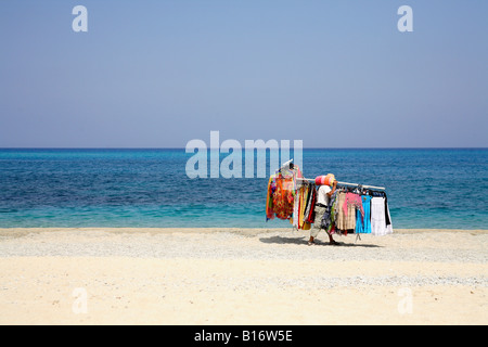 ein Strand-Verkäufer Spaziergänge entlang der Sand tragen eine große Last von waren, an Torists und Urlauber zu verkaufen. Stockfoto