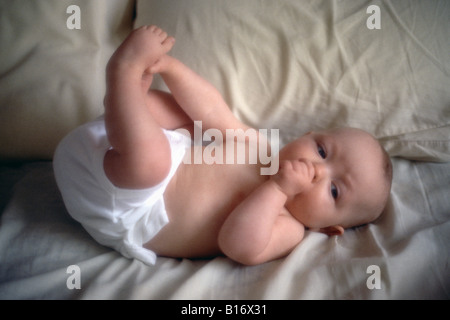 Baby in Windeln auf Bett Stockfoto