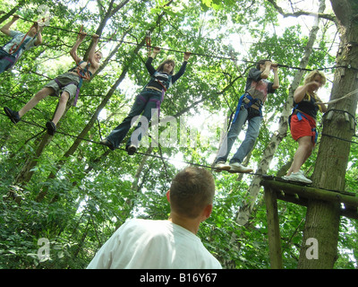 Studenten, die zu Fuß über Seil in den Bäumen am Schullandheim Stockfoto