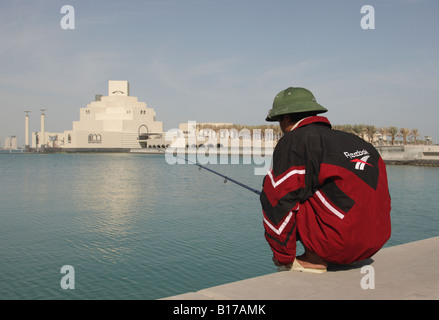 Mann, die Fischerei vor der Corniche Wit das Museum für islamische Kunst in Doha, Katar, bauen von dem Architekten I.M.Pei, im Hintergrund. Stockfoto