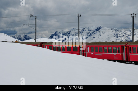 Helle rote Waggons vom Schnee bedeckt Berghänge in den Schweizer Alpen. Voller Touristen im Urlaub Skifahren. Stockfoto