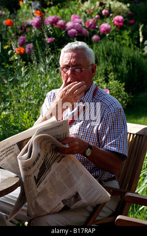 Mann liest eine Zeitung im Garten Stockfoto