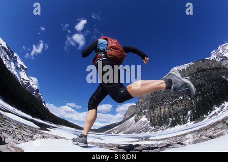 Eine junge Frau Trailrunning im Frühjahr nahe dem Ufer des Moraine Lake in Lake Louise, Banff Nationalpark, Alberta, Kanada. Stockfoto