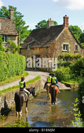 Junge weibliche Reiter voran durch Ford über den Bybrook Bach in Lacock Stockfoto