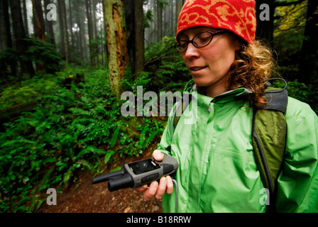 Frau Wanderungen Baden Powell Trail mit einem GPS-Gerät an einem regnerischen Nachmittag. North Vancouver, British Columbia, Kanada Stockfoto