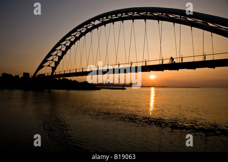 Radfahrer kreuzen Humber River Fußgängerbrücke bei Sonnenaufgang mit Toronto Skyline im Hintergrund, Toronto, Ontario, Kanada. Stockfoto