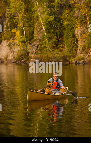 Junger Mann mit Hund auf Habichtsbitterkraut See Kanu fahren im Herbst, Mukoka, Ontario, Kanada. Stockfoto