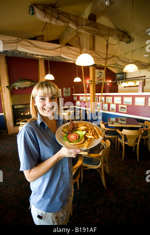 Weibliche Server auf dem Quarterdeck Pub mit einer Hamburger Platte.  Port Hardy, Vancouver Island, British Columbia, Kanada. Stockfoto