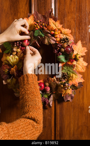 Hände, die Vermittlung von herbstlichen Kranz hängen, Holztür, Montreal, Quebec, Kanada Stockfoto