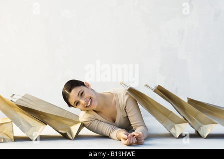 Frau unter Einkaufstüten, stützte sich auf der einen Seite in die Kamera Lächeln Stockfoto