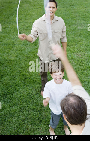 Jungen spielen Springseil mit zwei Männer, Lächeln, beschnitten Ansicht Stockfoto