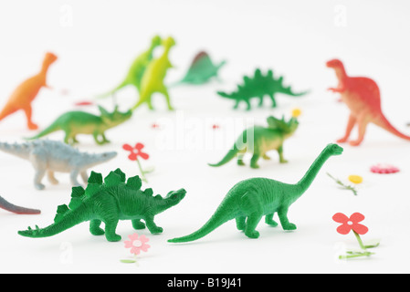 Spielzeug Dinosaurier umgeben von Kunstblumen Stockfoto
