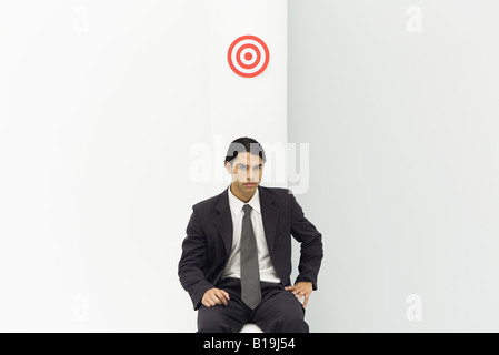 Junger Geschäftsmann sitzt unten Bullauge, Blick in die Kamera Stockfoto