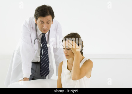 Frau mit Kopf, Arzt lehnt sich hinter ihr Stockfoto