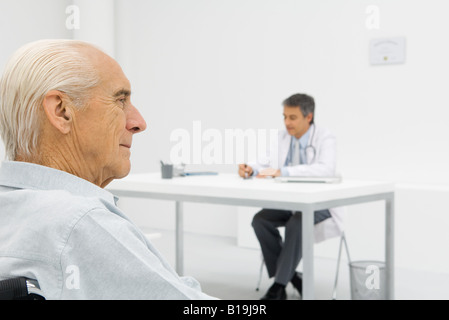 Arzt arbeiten am Schreibtisch, Fokus auf ältere Patienten im Vordergrund Stockfoto