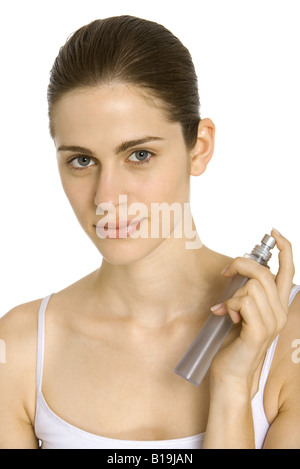 Junge Frau sprühen Parfüm auf Hals, lächelnd in die Kamera Stockfoto